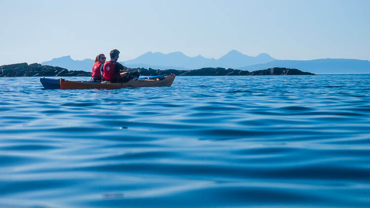 Kayaking couple on blue sea neat Small Isles