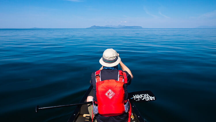 Bow canoeist wildlife watching towards Rum and Eigg
