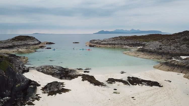 Kayaks on turquoise water and sandy beach at Eilean Shona